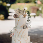 Fine Art Hochzeitstorte in Weiß und Gold mit Trockenblumen.
